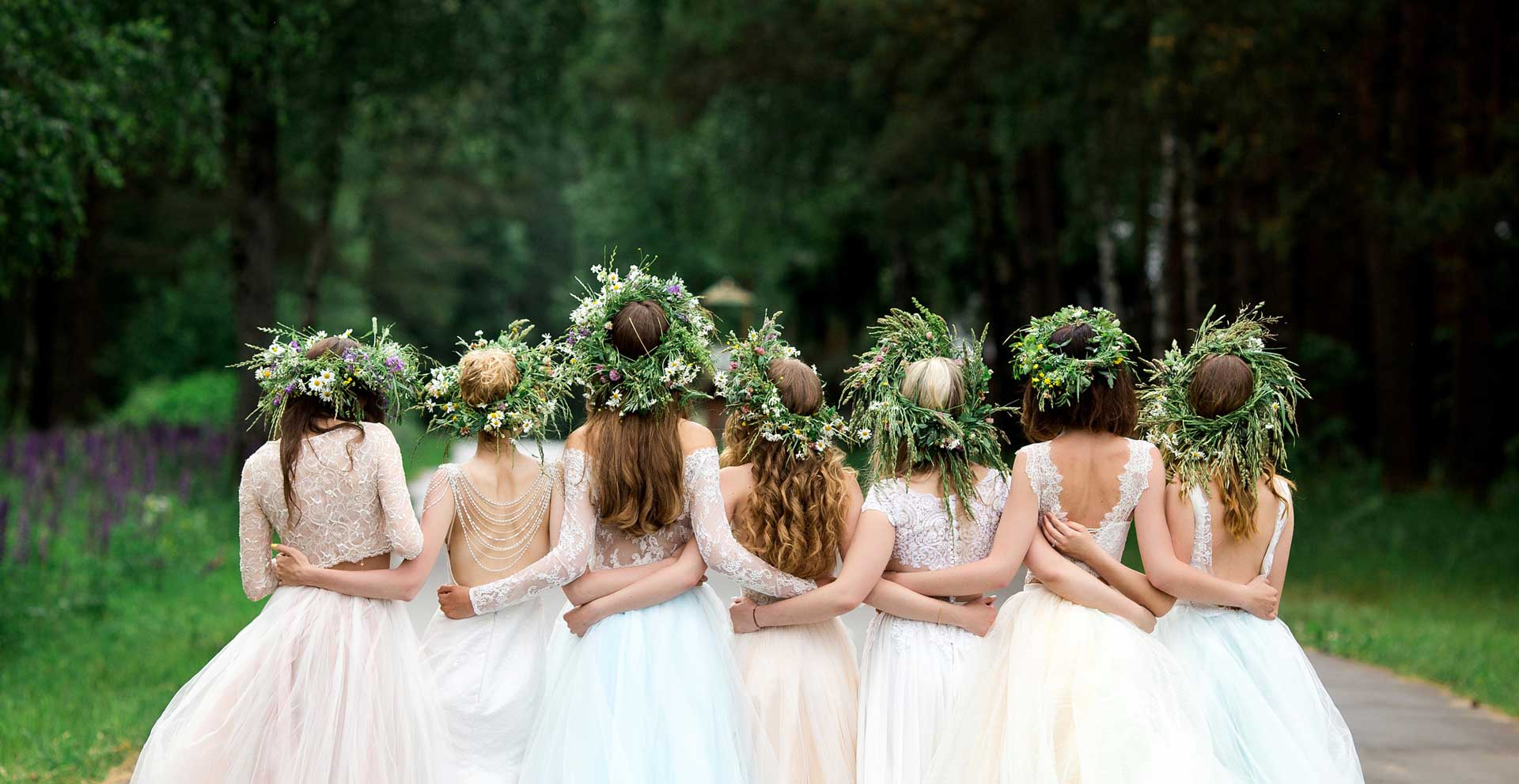 a group of women wearing white dresses with flowers on their head