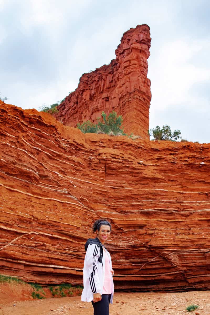 a woman standing in front of a red rock formation