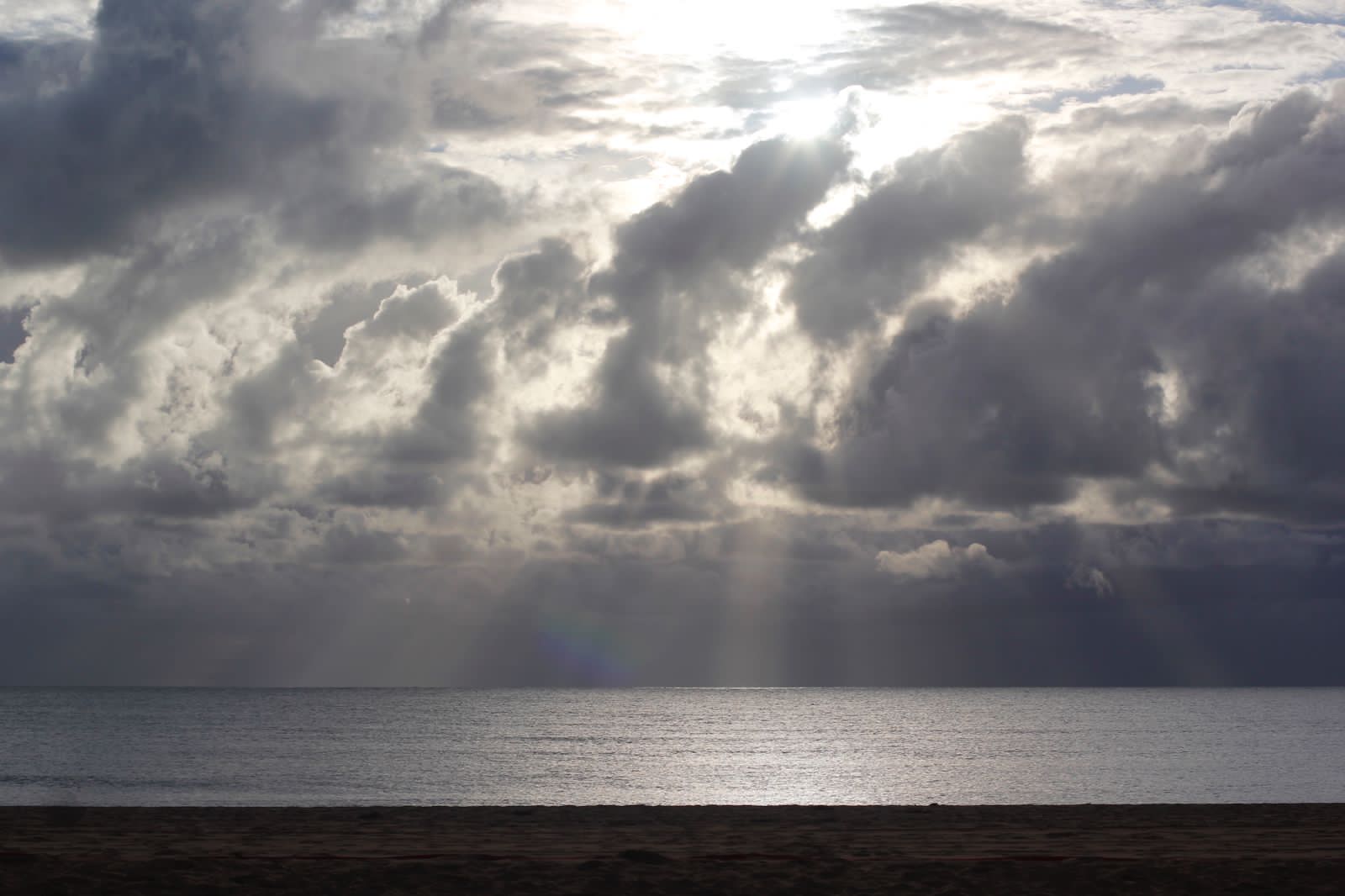 a beach with clouds and sun rays