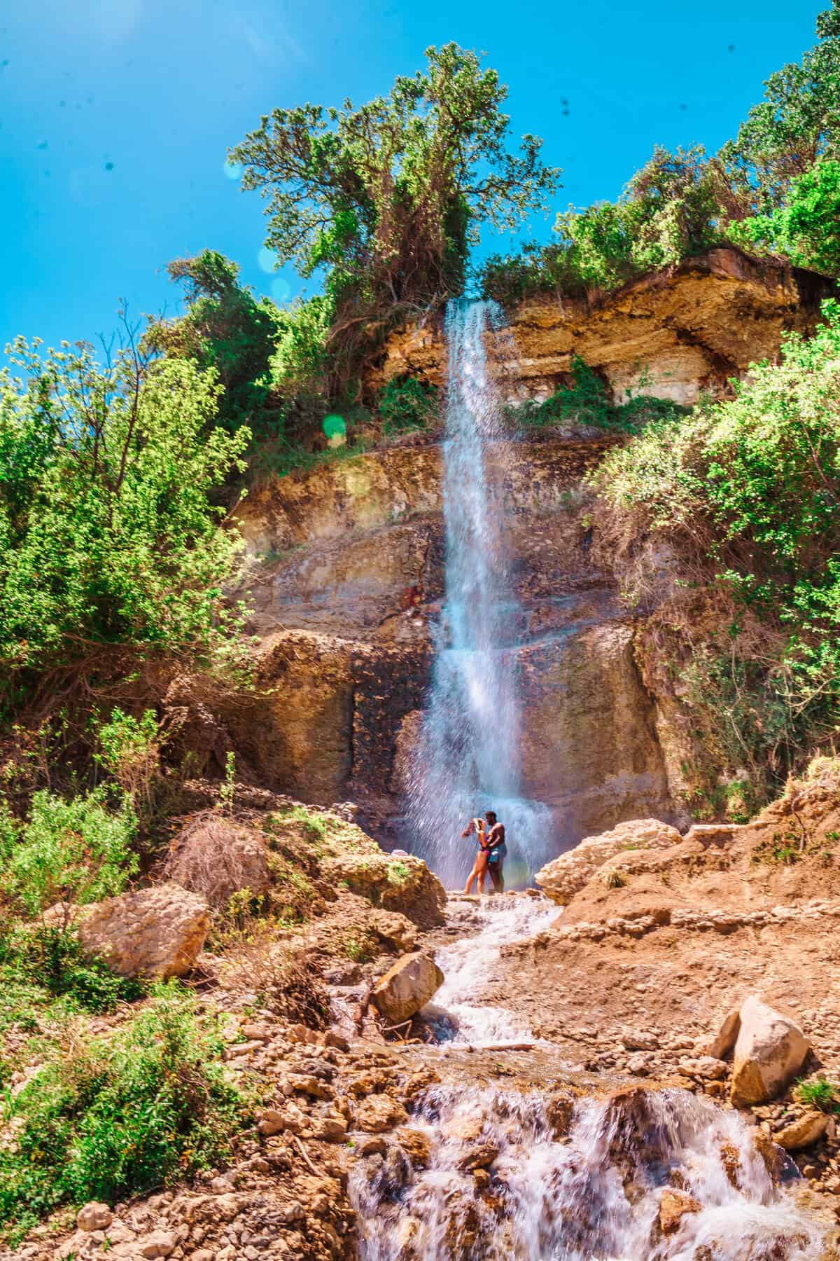 a man and woman standing next to a waterfall