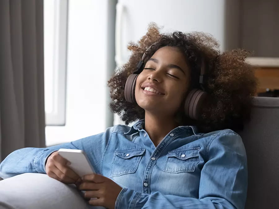 a woman with curly hair wearing headphones and holding a phone