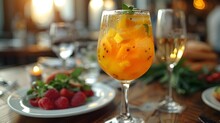 a glass of orange juice and fruit on a table