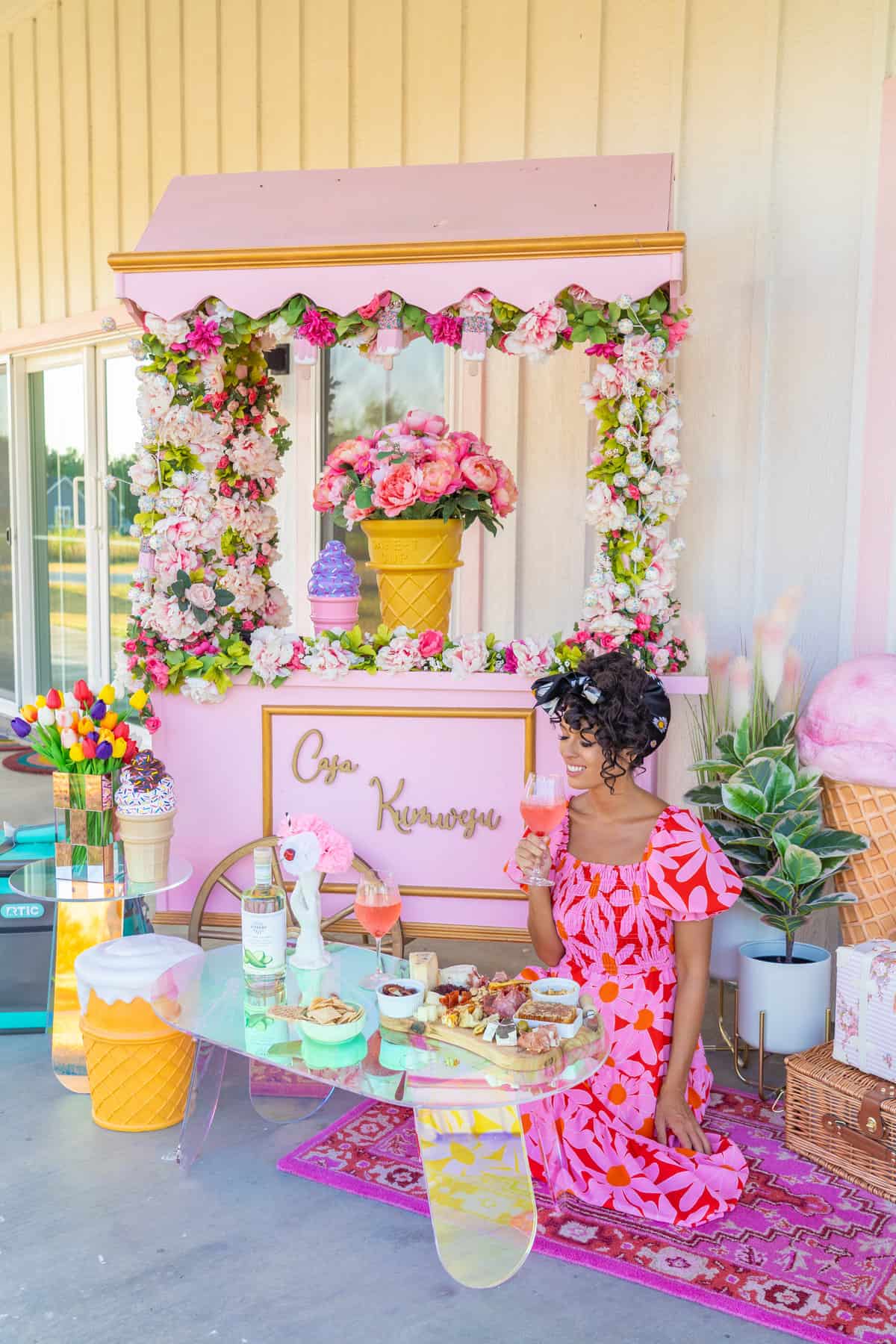 a woman holding a drink in front of a pink ice cream cart